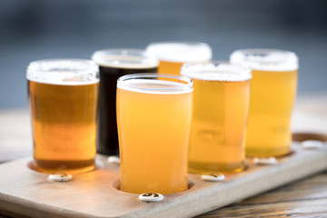 Flight of six craft beer in pint glasses on a wood tray