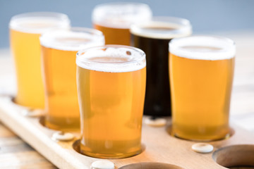 Flight of craft beer in pint glasses on a wood tray