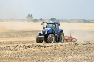 Obraz premium Tractor preparing land with plow, sunny summer day at agricultural field