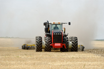 Obraz premium Tractor preparing land with plow, sunny summer day at agricultural field