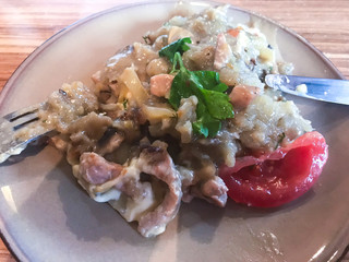 Hot pan with potatoes, meat, gravy and tomatoes