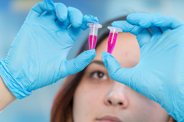 Female medical worker compares test tubes with biological samples