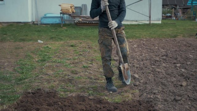 A man digs the ground with a shovel