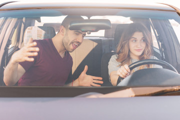Driving test. Male instructor teaches inexperienced female trainee drive car, controls everything...