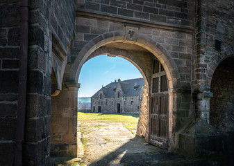 Fototapeta na wymiar Crooked castle gate allowing a view inside the premises