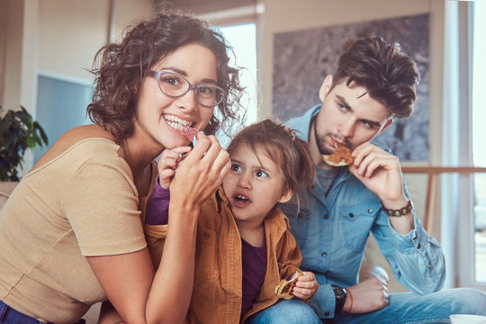 Family Breakfast. Young attractive family having breakfast at home sitting on a sofa.
