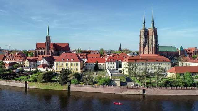 Poland. Wroclaw. Ostrow Tumski, Gothic cathedral of St. John the Baptist,  Collegiate Church of the Holy Cross and St. Bartholomew, park, Odra (Oder) River and kayak. Aerial 4K footage at sunset