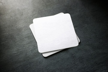 Blank white beer coaster stack mockup, top view, lying on the textured background. Squared clear can mat design mock up isolated. Quadrate cup rug display - obrazy, fototapety, plakaty