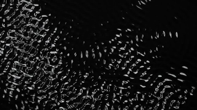 Vibrations and dark water liquid over a subwoofer audio speaker. Black background. Slow motion