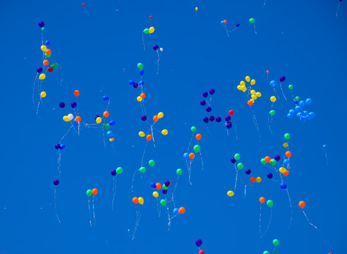 Multicolored balls, filled with helium, fly in the blue sky.