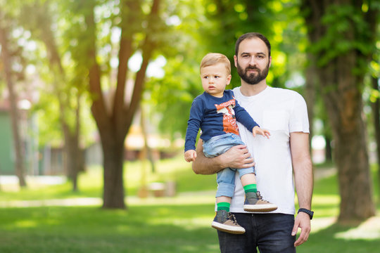 Father holding his toddler son outdoors in park on sunny spring day. Natural lighting, no retouch, closeup, vibrant colors