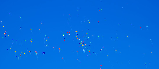 Multicolored balls, filled with helium, fly in the blue sky.