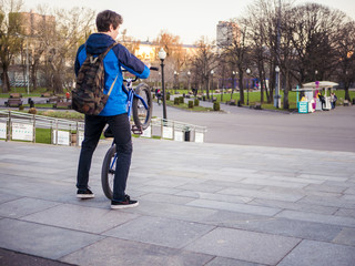 young man walking in the urban street of the city with bmx