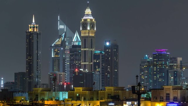 Modern Dubai city skyline timelapse at night with illuminated skyscrapers over water surface