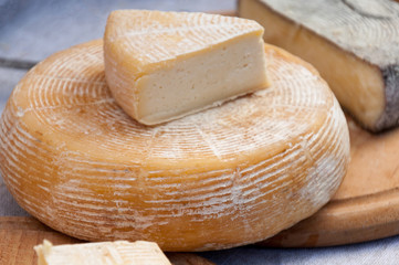 Round cheese and cut piece on a cutting board