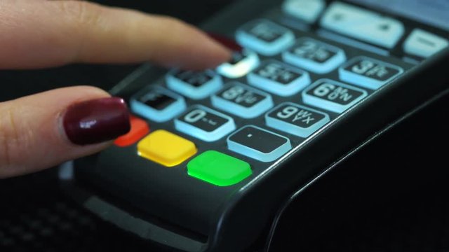 Shop assistant inserting a credit card into a pos and inserting pin-code of the card