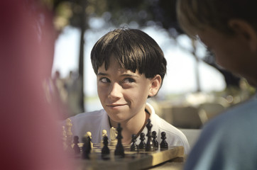 A young boy giving a side glance while at a game of chess.