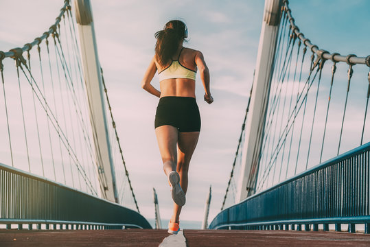 Young fit blonde woman running on the bridge