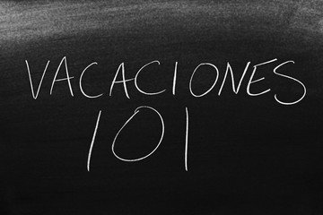 Obraz premium The words Vacaciones 101 on a blackboard in chalk. Translation: Vacation 101