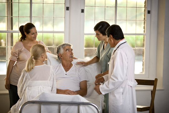 Elderly man receiving a hospital visit from his family.