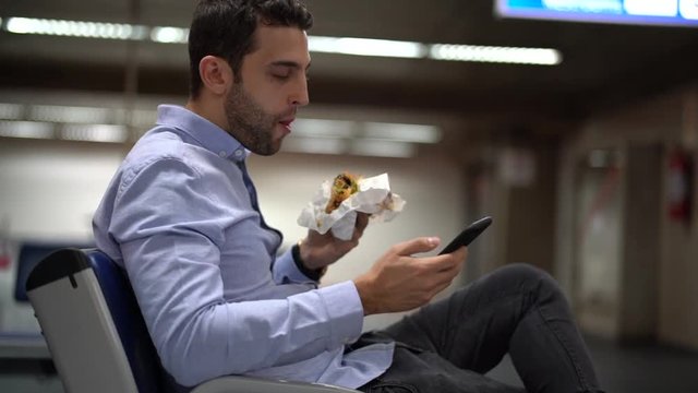 Guy eating sandwich at airport