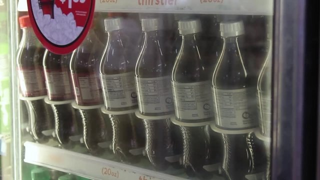 Grabbing a soda bottle from a refrigerated case at a convenience store
