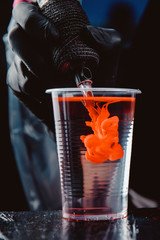 Close-up of tattoo machine is washed with needles in clear water from pigment of paint.