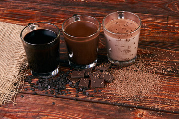 Glasses of chocolate milkshake on wooden table closeup, sweet dessert food 
