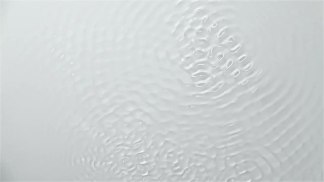 Reflection of the water creating waves caused by sound vibrations. White background. Slow motion