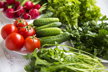 Set of different organic ingredients for salad making: tomatoes, radish, cucumber, arugula, lettuce, side view. Healthy food concept.