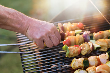 close-up of a barbecue where chicken skewers are being cooked.