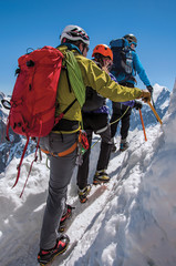 Close-up of climbers walking on snowy path in a sunny day at the Aiguille du Midi, near Chamonix. A famous ski resort located in Haute-Savoie Province, at the foot of Mont Blanc in the French Alps.