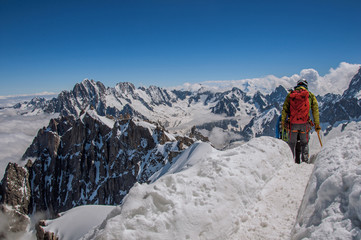 Climber walking on snow in a sunny day at the Aiguille du Midi, near Chamonix. A famous ski resort located in Haute-Savoie Province, at the foot of Mont Blanc in the French Alps.