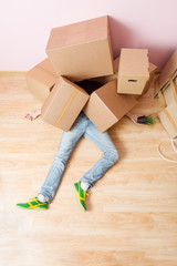 Photo of man in jeans lying under cardboard boxes