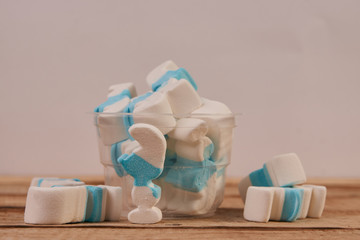 Marshmallow in a plastic glass on wooden table background, close-up. Sweet unhealthy snack