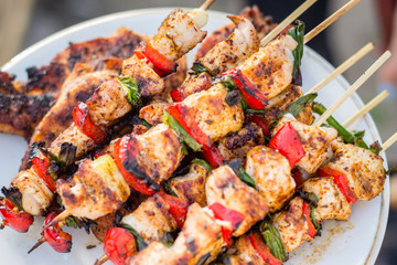 Close up pf delicious chicken breast on wooden skew with fresh vegetables, garlic, paprika fried on mangal barbeque grill