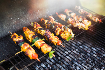 close-up of a barbecue where chicken skewers are being cooked.