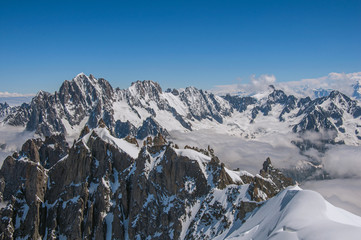 Snowy peaks and mountains in a sunny day, viewed from the Aiguille du Midi, near Chamonix. A famous ski resort located in Haute-Savoie Province, at the foot of Mont Blanc in the French Alps.