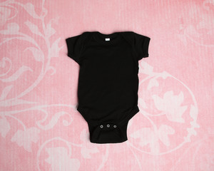 Mockup of blank black baby bodysuit tshirt on pink background