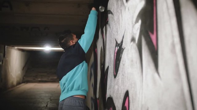 Graffiti artist painting on the wall in subway