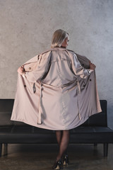 back view of beautiful blonde woman in stockings and high heeled shoes taking off coat