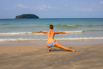 Woman doing yoga on empty beach. Tropical seaside vacation activity. Young girl in asana posture.