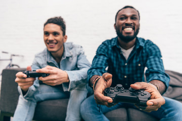 multiethnic male friends with joysticks playing video game