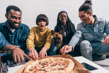 smiling young multicultural friends with french bulldog taking pizza