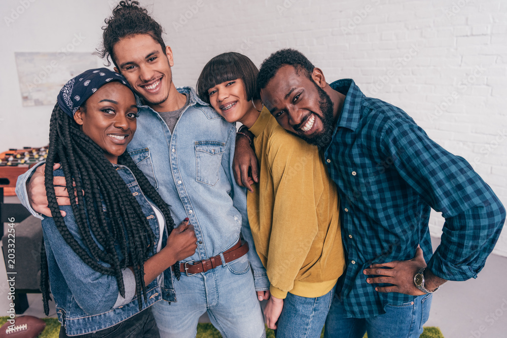 Wall mural young smiling group of multiethnic friends embracing each other