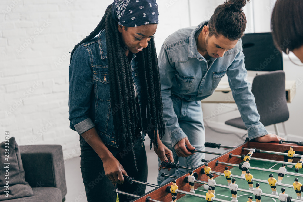 Wall mural cropped shot of young multiethnic group of friends playing table football