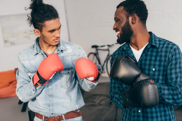 young multicultural male friends boxing in gloves