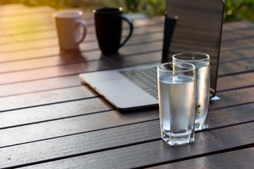 Cold water in clear glass with a garden in the background. The concept of healthy drinking during work