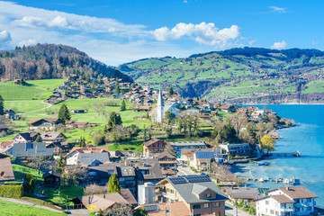 Naklejka premium Brienz town on Lake Brienz by Interlaken, Switzerland, with snow covered Alps mountains in background