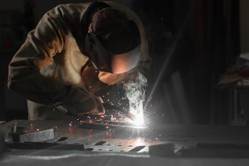 worker in protection mask welding metal at factory - obrazy, fototapety, plakaty